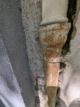Rusty metal pipe joint in weathered concrete wall close up texture detail mac Stock Photos