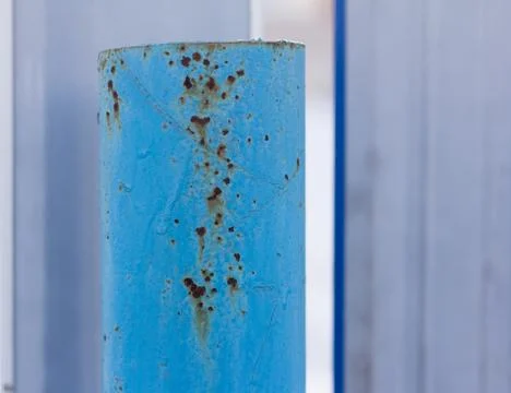A rusty metal pipe, Rust through the blue paint on an iron post. Stock Photos
