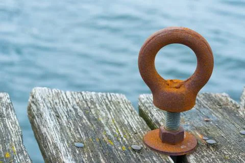 A rusty metal ring on a bolt mounted on a wooden pier.. Stock Photos