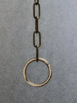 Rusty metal ring on hanging chain against textured gray wall Stock-Fotos