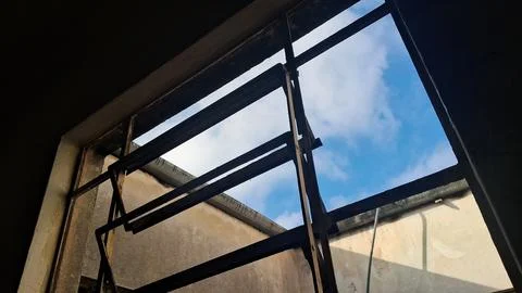 Rusty metal window frame looking out at a bright blue sky Stock Photos