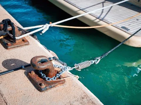 Rusty mooring bollards with chains and ropes tied to them in a harbour Stock Photos