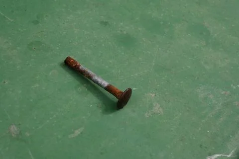 Rusty nail on a green surface Stock Photos