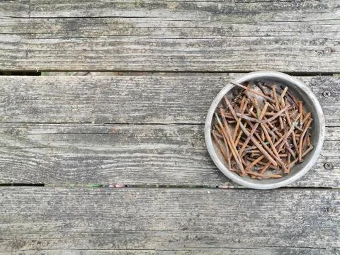 Rusty nails lie in an old iron bowl on a background of old boards Fotos de archivo
