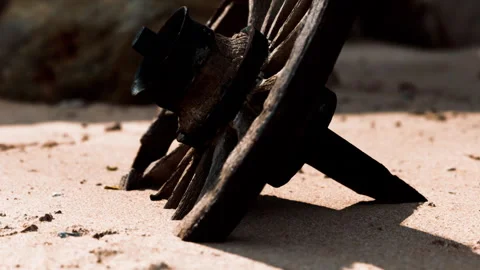Rusty object rests on sandy surface near rocks at beach during daytime Stock Footage 340612261
