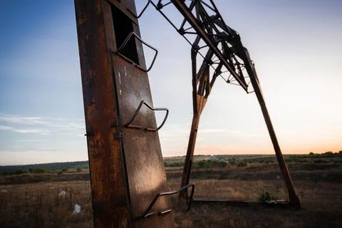 A Rusty Oil Pumpjack Against a Sunset Sky in a Desert Landscape Stock Photos
