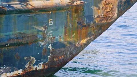 Rusty old barge sits in port with peeling paint and depth number markers visible Stock Footage 242862892