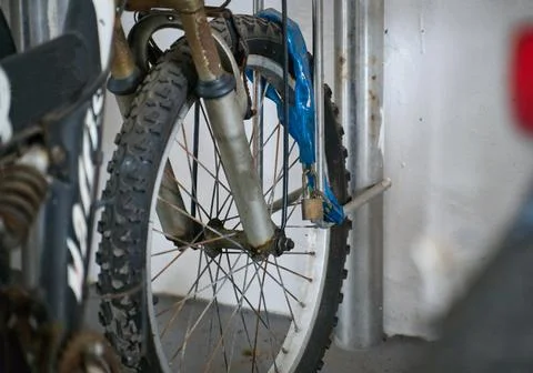 Rusty old bicycle front wheel locked and secured to metal bike stand. Foto stock