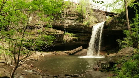 Rusty old bridge over a cave and waterfall Stock Footage 153874492