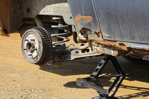 Rusty Old Car Up on Jack During a Tire Change Stock Photos
