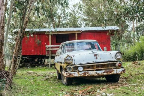 Rusty old car parked in front of an old Railroad boxcar transformed into a sm Foto stock