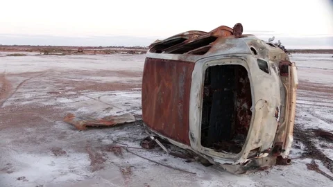 Rusty old car rolled on side on salt lake bed Vídeos de archivo 95734806