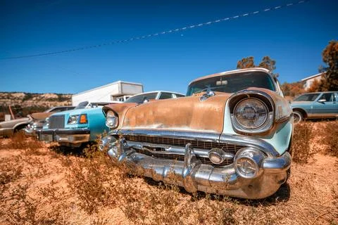 Rusty old cars under a blue sky. Old vintage vehicles in the countryside Stock Photos