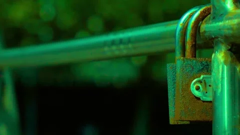Rusty old metal padlock locked to a fence in the dark with green light Stock-Footage 341801519
