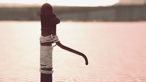 Rusty old metal water pump on sand beach Stock Footage 238456349