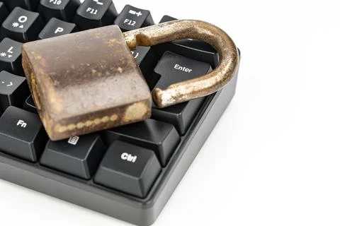 Rusty old padlock resting on computer keyboard enter key, cybersecurity concept Stock Photos