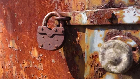 Rusty Old Padlock Securing a Corroded Metal Door Stock Footage 335956172