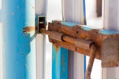 Rusty old slide bolt or tower bolt on a worn green door. Stock Photos