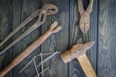 Rusty old tools are laid out on black vintage wood background. Stock Photos