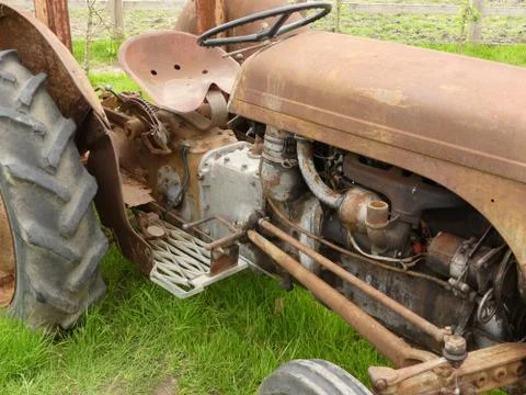 A rusty old tractor sitting in a grass area in England Stock Photos