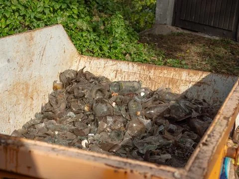 Rusty Outdoor Dumpster Filled with Broken Clear Glass for Recycling Stock Photos