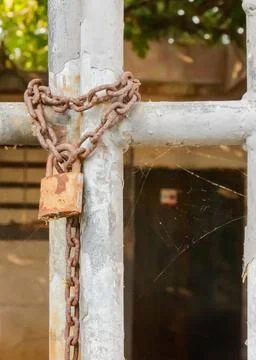 Rusty padlock and chain securing a gate in an abandoned location during mid.. Stock Photos