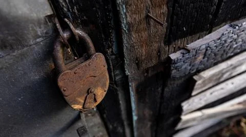 A rusty padlock is currently hanging on an old wooden door Stock Photos