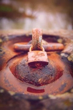 Rusty padlock locked around an aged iron ring Stock Photos