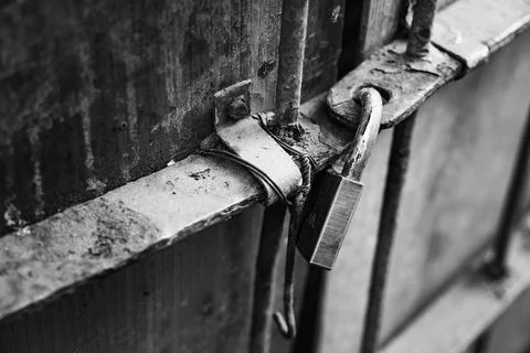 Rusty padlock secured on an old wooden door with peeling paint and wear marks Stock Photos