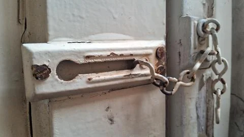 Rusty padlock securing a metal door. Close-up of a weathered lock and chain for Stock Photos