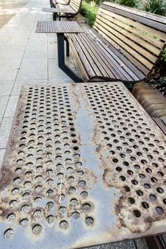 Rusty park bench tables constructed using iron plates, with perforated holes. Stock Photos