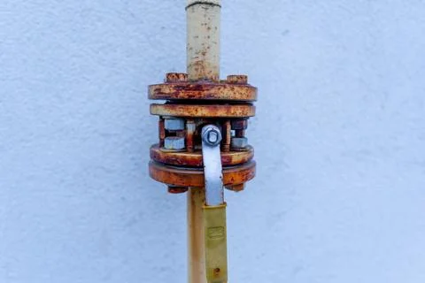 Rusty Pipe Fitting Attached to a White Wall Showing Signs of Wear and Age D.. Stock Photos