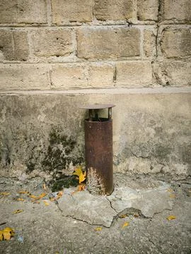A rusty pipe is leaning against a brick wall.  Stock Photos