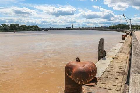 A rusty pipe is sitting in the water next to a pier in Bordeaux France Stock Photos