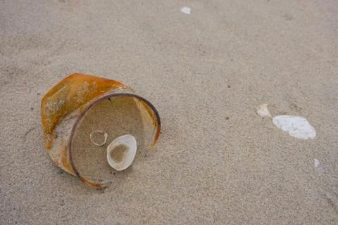 Rusty plastic cup on a sand after sea storm. Environmental pollution. Stock Photos