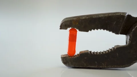 A rusty pliers with the red medicine capsule Stock Footage 129452216