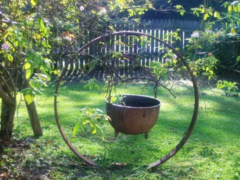 RUSTY POT INSIDE RUSTY CIRCLE ON GREEN GRASS ON A COOL SUNNY DAY Fotos Stock