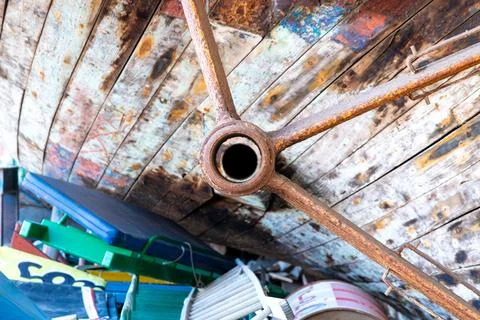 Rusty propeller shaft beneath weathered wooden ship hull Stock Photos