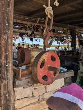 Rusty pulley hoist hanging inside rustic seaside bar with blurred crowd Stock Photos