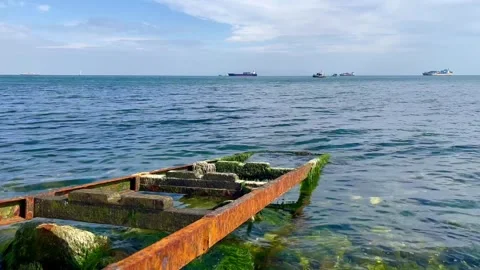 Rusty rails go into the blue sea water - stock video Stock Footage 240344997