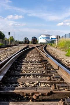 Rusty railway switch toward parked tank wagons under bright blue sky backgr.. Stock Photos