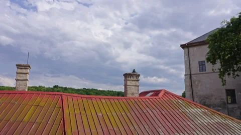 Rusty Rooftop and Stone Chimneys Under Moody Summer Sky Stock Footage 313882371