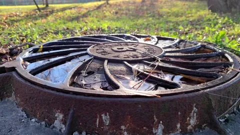 Rusty sewer iron hatch with water from the rain in the autumn city park. Russia Stock Footage 164840516