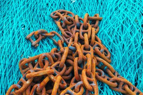 Rusty shackles on a blue fishing net Stock Photos