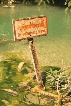 A rusty sign saying "Do not swim in this area" at the pools of the Kuang Si F Stock Photos