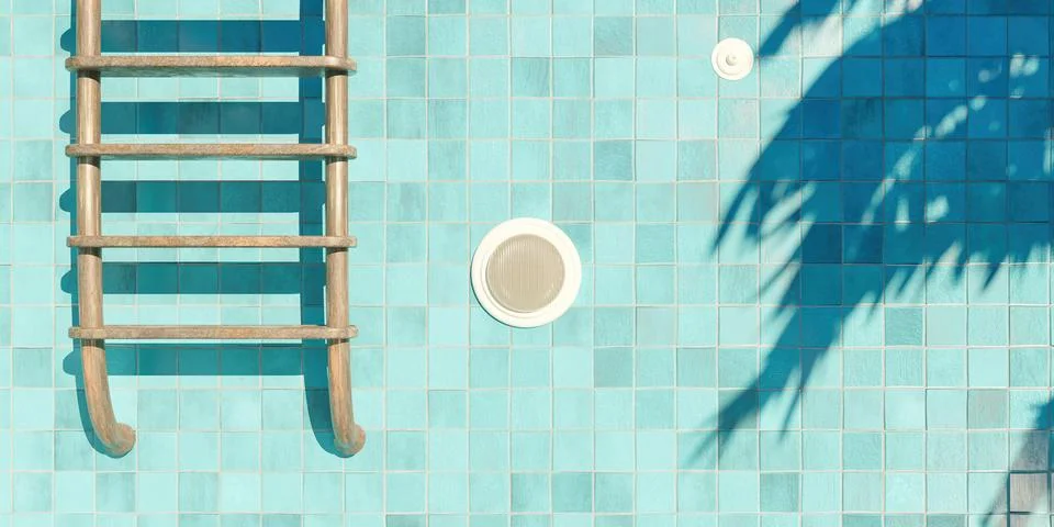 Rusty stairs in an empty blue tiled pool with a spotlight and palm tree shado Stock-Fotos