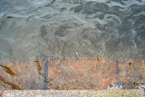 Rusty step visible through shallow transparent river water Stock Photos