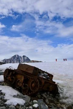 Rusty tank wreck in Antarctica with explorers in background Stock Photos