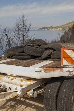 Rusty trailer loaded with tires overlooking a calm Croatian bay Stock-Fotos