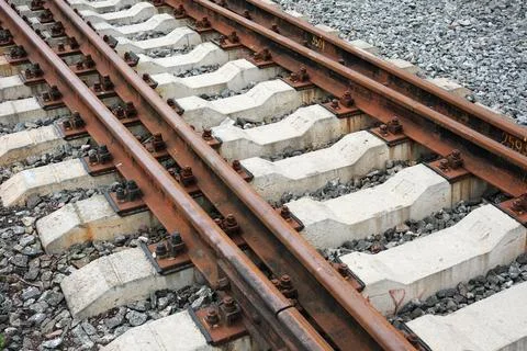 Rusty train tracks create a pattern of lines and textures in sunlight Stock Photos